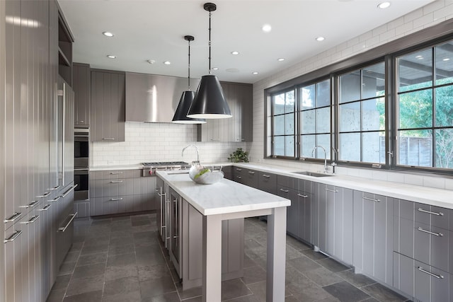 kitchen with extractor fan, a kitchen island, decorative light fixtures, sink, and decorative backsplash