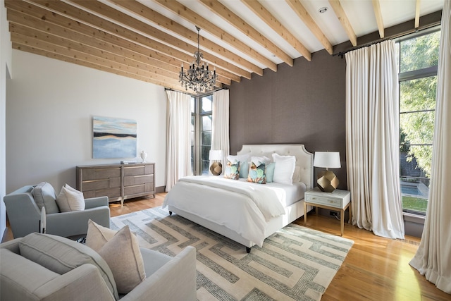 bedroom with light hardwood / wood-style flooring, beamed ceiling, and a chandelier