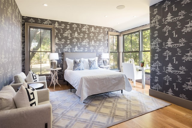 bedroom featuring multiple windows, hardwood / wood-style floors, and lofted ceiling