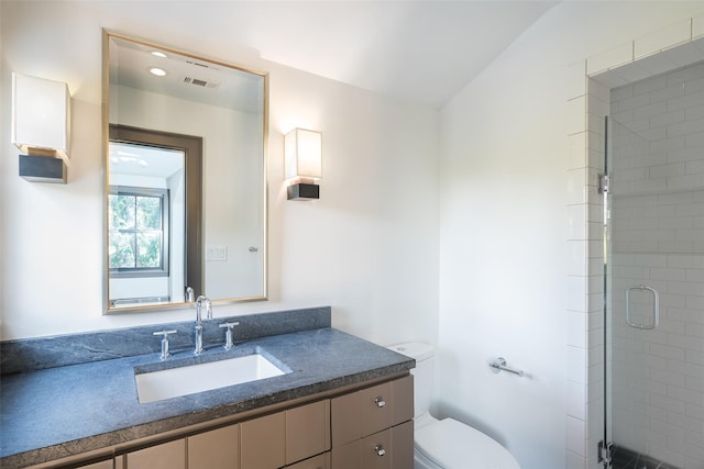 bathroom featuring vanity, an enclosed shower, and toilet