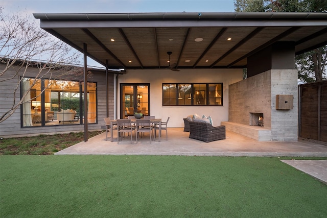 rear view of property featuring a patio, an outdoor living space with a fireplace, and a yard