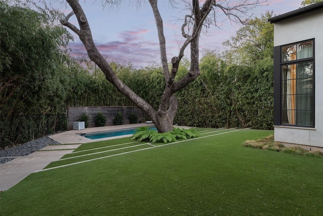 yard at dusk featuring a fenced in pool