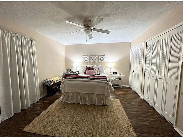 bedroom featuring ceiling fan, two closets, a textured ceiling, and dark hardwood / wood-style flooring