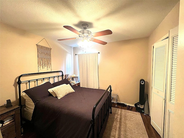 bedroom featuring ceiling fan, dark hardwood / wood-style flooring, a closet, and a textured ceiling