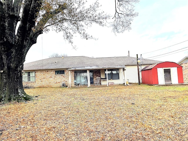 rear view of property with a lawn and a storage unit