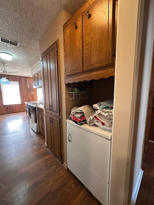 kitchen featuring wooden walls, white electric range oven, dark hardwood / wood-style flooring, and a textured ceiling