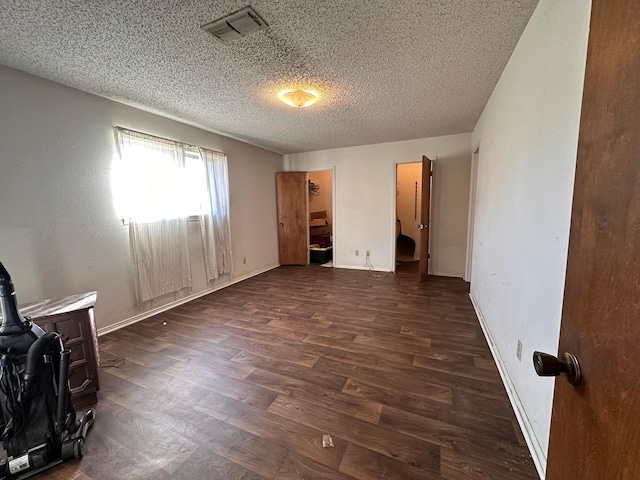 unfurnished bedroom featuring a textured ceiling and dark hardwood / wood-style flooring