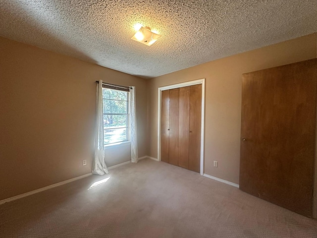 unfurnished bedroom featuring baseboards, a closet, carpet flooring, and a textured ceiling
