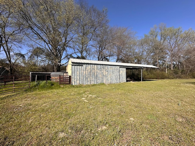 view of yard featuring an attached carport, an outbuilding, and fence