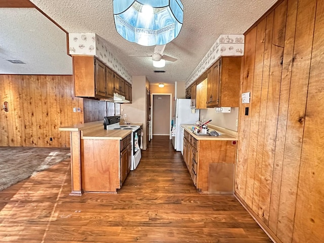 kitchen featuring wooden walls, white appliances, dark hardwood / wood-style floors, and a textured ceiling