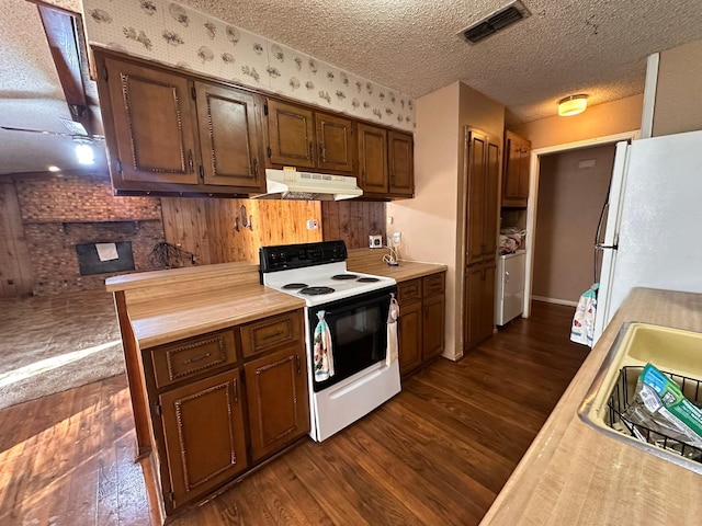 kitchen featuring dark wood-type flooring, independent washer and dryer, butcher block countertops, a textured ceiling, and white appliances