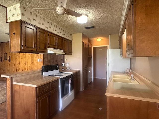 kitchen featuring light countertops, a sink, white range with electric cooktop, under cabinet range hood, and visible vents