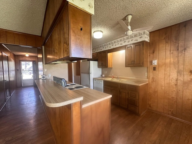 kitchen with dark wood-type flooring, ceiling fan, brown cabinets, and white appliances
