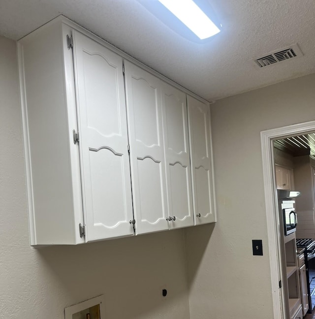 laundry room featuring cabinets, electric dryer hookup, and a textured ceiling