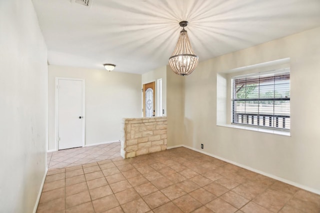 tiled empty room with a notable chandelier