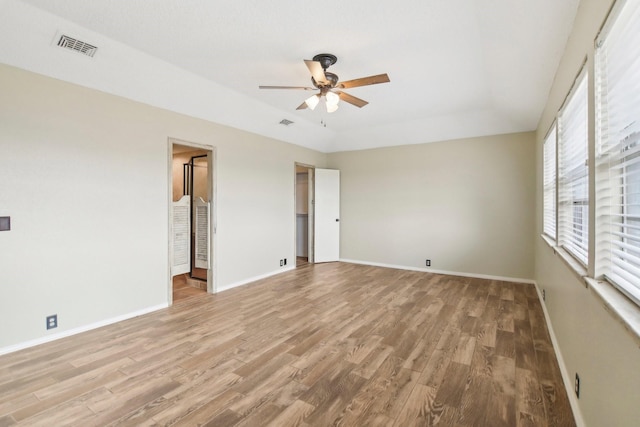 empty room with light hardwood / wood-style flooring, a raised ceiling, and ceiling fan