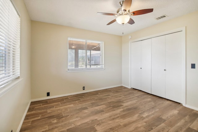 unfurnished bedroom with wood-type flooring, a closet, and ceiling fan