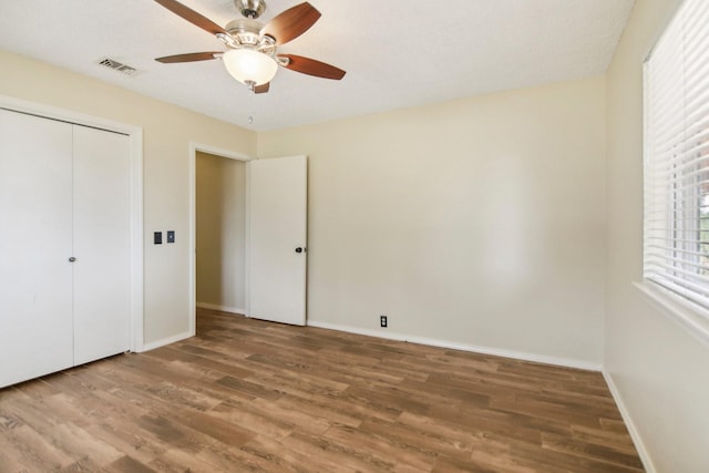 unfurnished bedroom with hardwood / wood-style floors, a closet, and ceiling fan