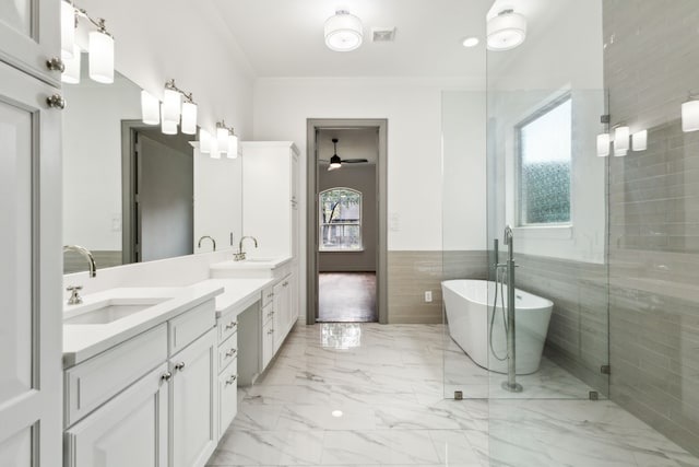 bathroom with marble finish floor, double vanity, a sink, and a wealth of natural light