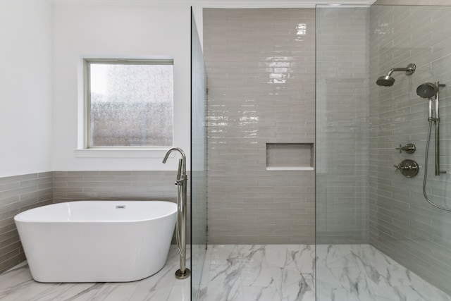 bathroom featuring a soaking tub, a tile shower, and marble finish floor