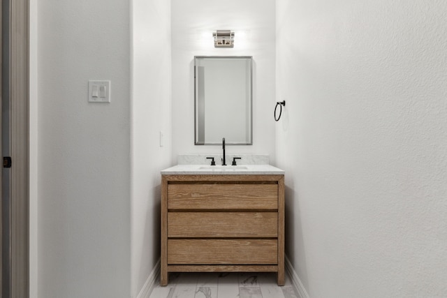 bathroom with marble finish floor, baseboards, and vanity