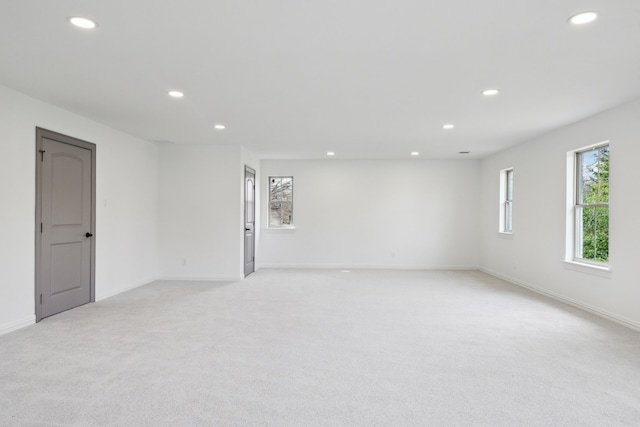 spare room featuring recessed lighting, light carpet, and baseboards