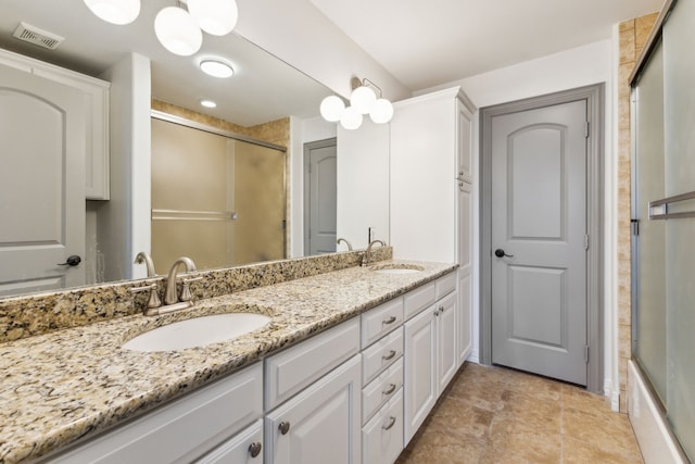 bathroom with a shower with door, a sink, visible vents, and double vanity