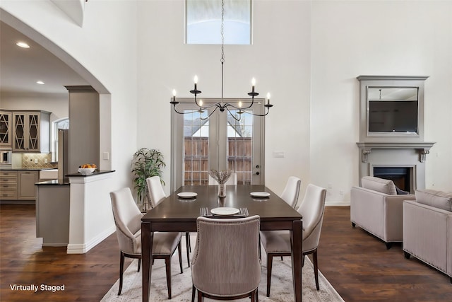 dining room featuring a fireplace, dark wood finished floors, baseboards, and an inviting chandelier