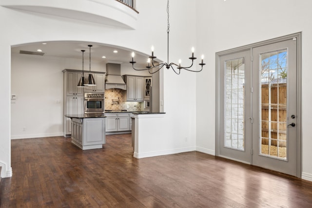 kitchen with a wealth of natural light, dark countertops, premium range hood, and stainless steel oven