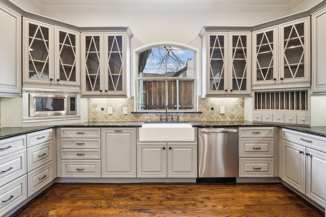 kitchen with stainless steel appliances, a sink, dark wood-style floors, glass insert cabinets, and crown molding