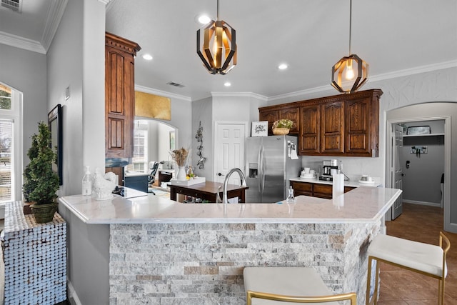 kitchen with crown molding, stainless steel fridge, a breakfast bar area, decorative light fixtures, and kitchen peninsula