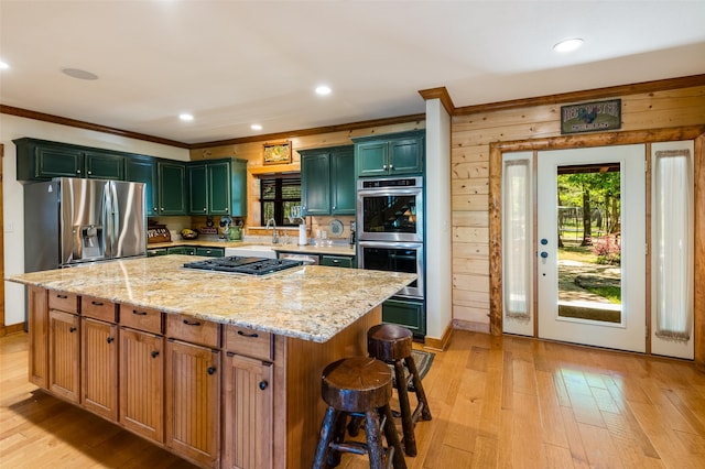 kitchen with appliances with stainless steel finishes, light stone countertops, light hardwood / wood-style floors, and a kitchen island