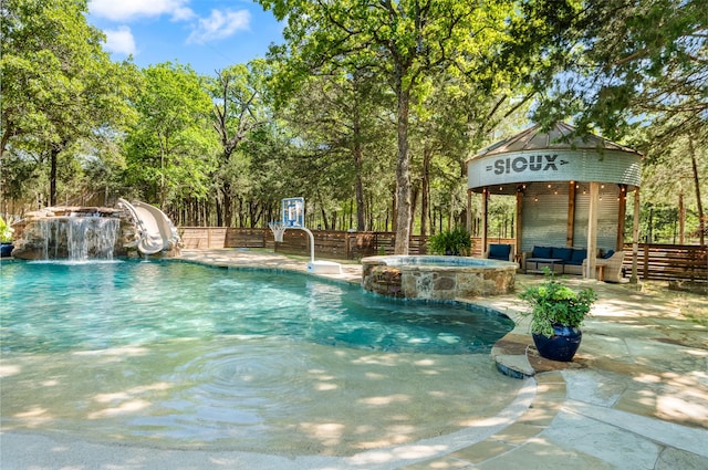 view of pool with pool water feature, a water slide, outdoor lounge area, an in ground hot tub, and a patio