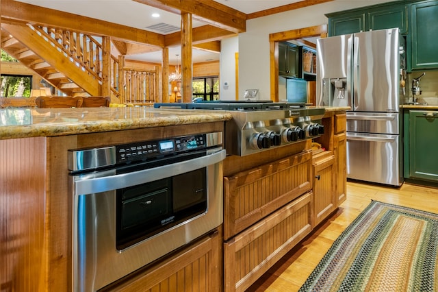 kitchen with sink, light wood-type flooring, appliances with stainless steel finishes, beamed ceiling, and light stone countertops