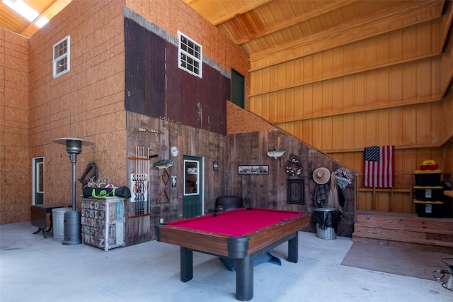 game room with concrete flooring, pool table, high vaulted ceiling, and wood walls