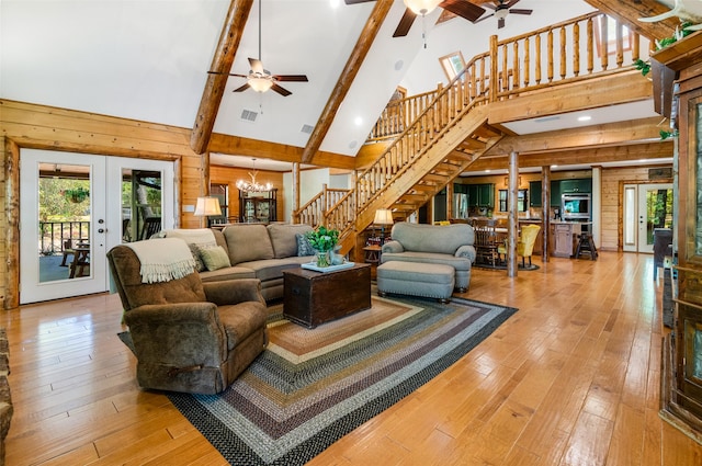 living room featuring high vaulted ceiling, wooden walls, light wood-type flooring, and french doors