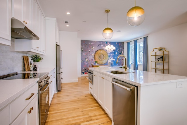 kitchen featuring sink, decorative light fixtures, appliances with stainless steel finishes, an island with sink, and white cabinets