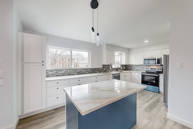 kitchen with a kitchen island, pendant lighting, white cabinets, backsplash, and stainless steel appliances