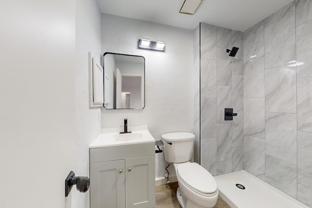 bathroom featuring vanity, toilet, and a tile shower