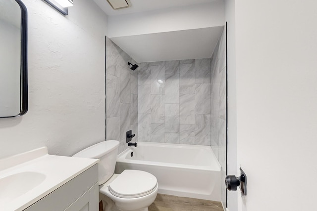 full bathroom featuring vanity, tiled shower / bath combo, and toilet