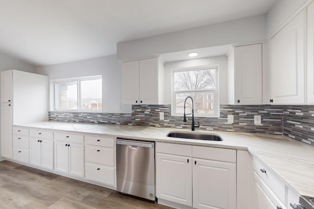 kitchen featuring tasteful backsplash, dishwasher, sink, white cabinets, and light hardwood / wood-style flooring