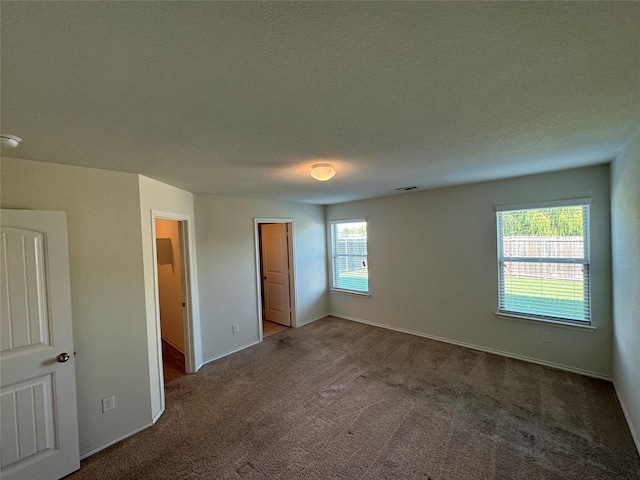 unfurnished bedroom with a textured ceiling and dark carpet