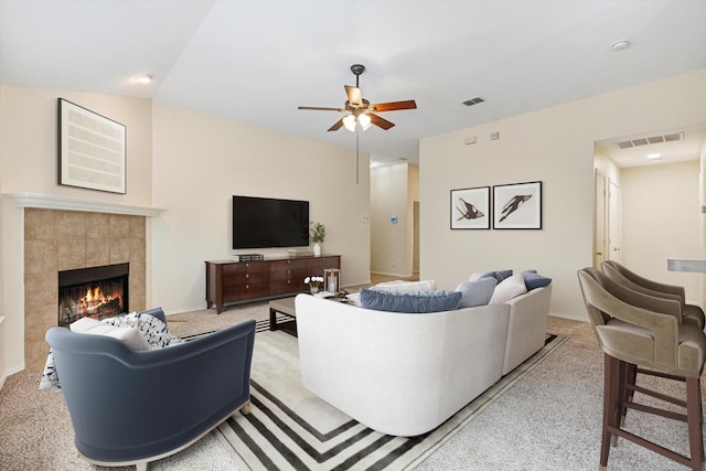 living room featuring ceiling fan, light colored carpet, and a fireplace