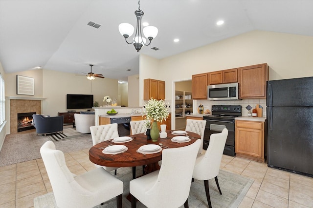 tiled dining area featuring a fireplace, ceiling fan with notable chandelier, vaulted ceiling, and sink