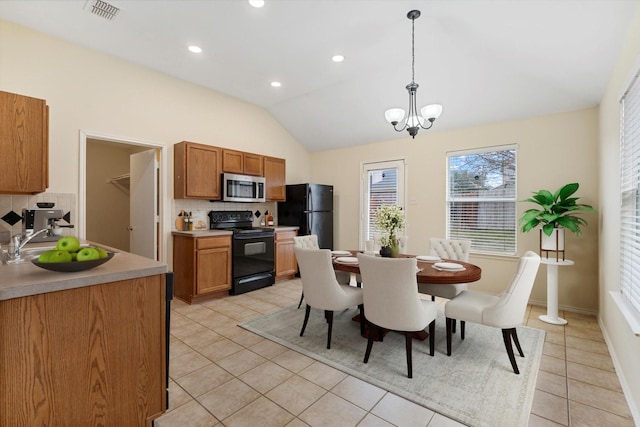 kitchen with light tile patterned flooring, vaulted ceiling, a chandelier, hanging light fixtures, and black appliances