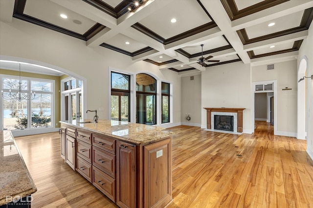 kitchen featuring beamed ceiling, light stone countertops, sink, and light hardwood / wood-style floors