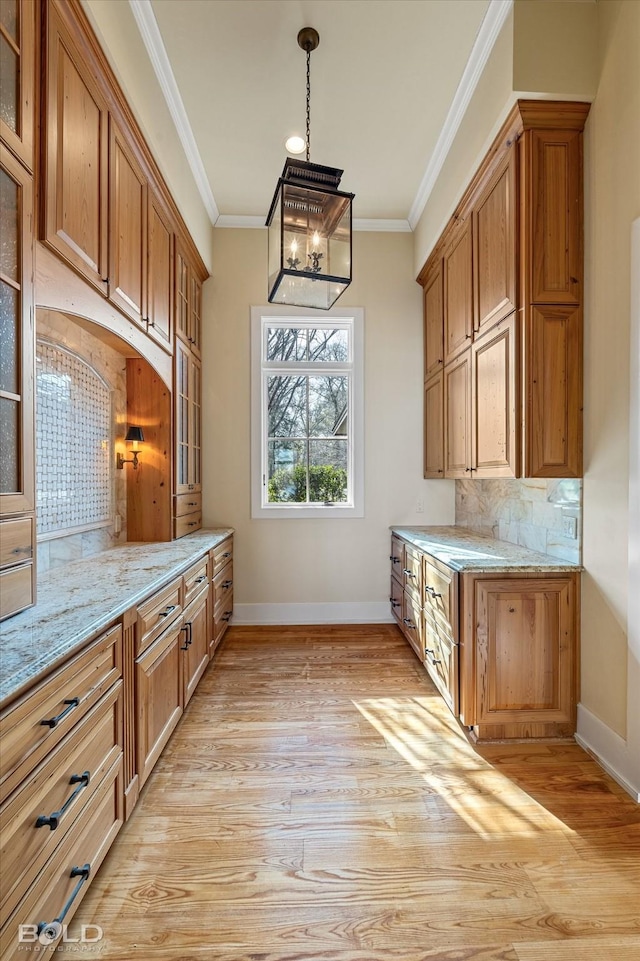 kitchen featuring crown molding, tasteful backsplash, light stone countertops, and hanging light fixtures