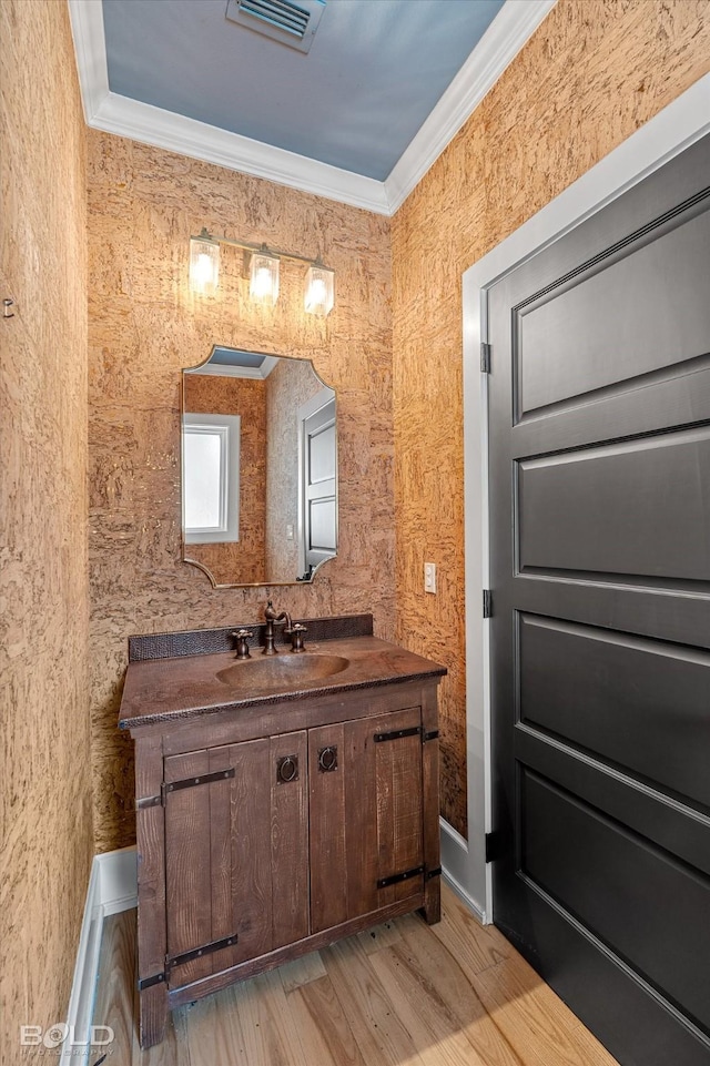 bathroom featuring crown molding, wood-type flooring, and vanity