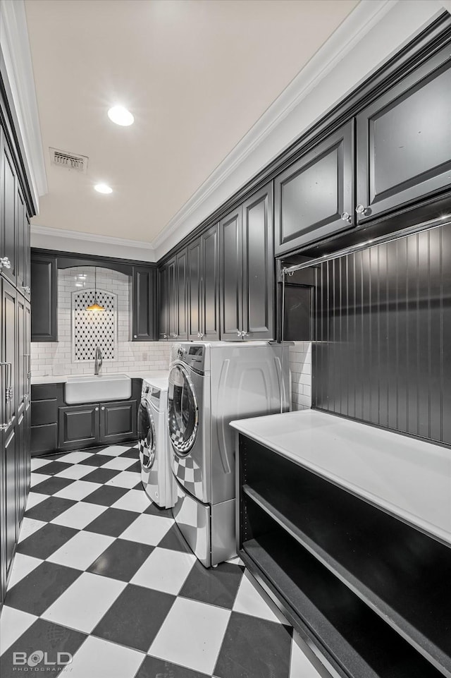 laundry area featuring sink, crown molding, washer and clothes dryer, and cabinets