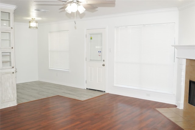 foyer featuring a tiled fireplace, wood-type flooring, ornamental molding, and ceiling fan